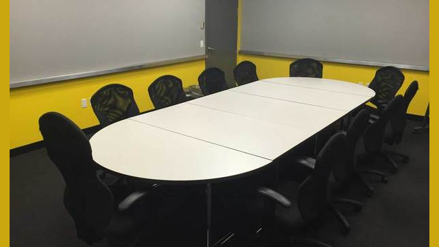 Focus group room with conference table and chairs, walls that can accommodate push pins and bright yellow paint.