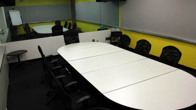 Focus group room configured with conference table and chairs, showing one way mirror.
