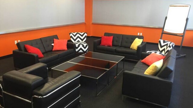Focus group room configured in a living room setup consisting of modern black sofas and showing the 2 tackable wall.