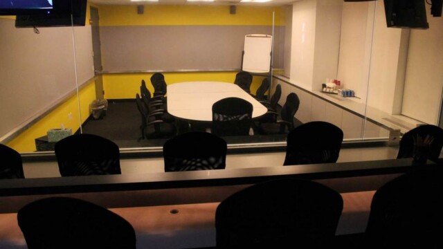 Focus group facility viewing room showing tiered seating and view of conference room through one-way mirror