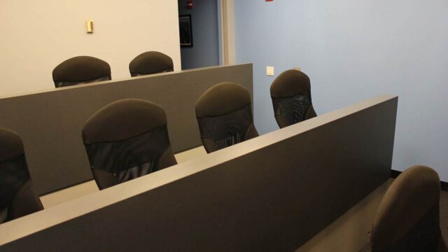 Focus group viewing room showing 2 tiers of seating for those observing what is taking place in the adjacent room. Each tier had a dark grey privacy top and black office chairs.